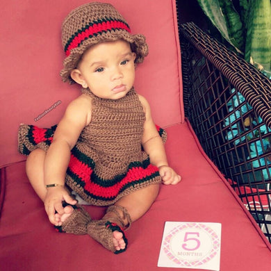 Baby girl wearing a crochet brown dress and hat with the red and green gucci stripe